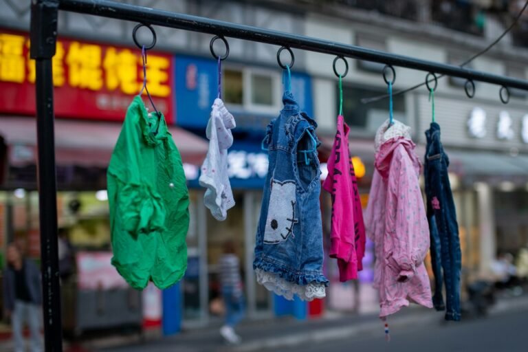 Colourful children's clothes and a denim vest hanging on a clothing rack
