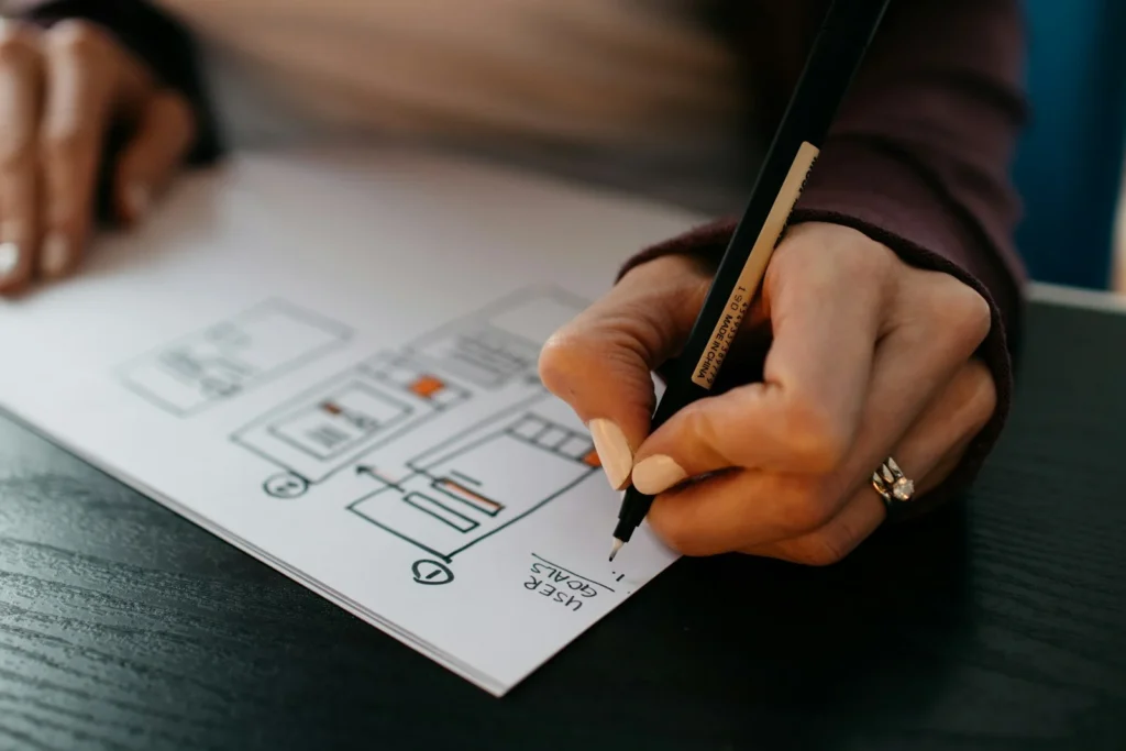 Designer sketching a website wireframe with a pen on paper